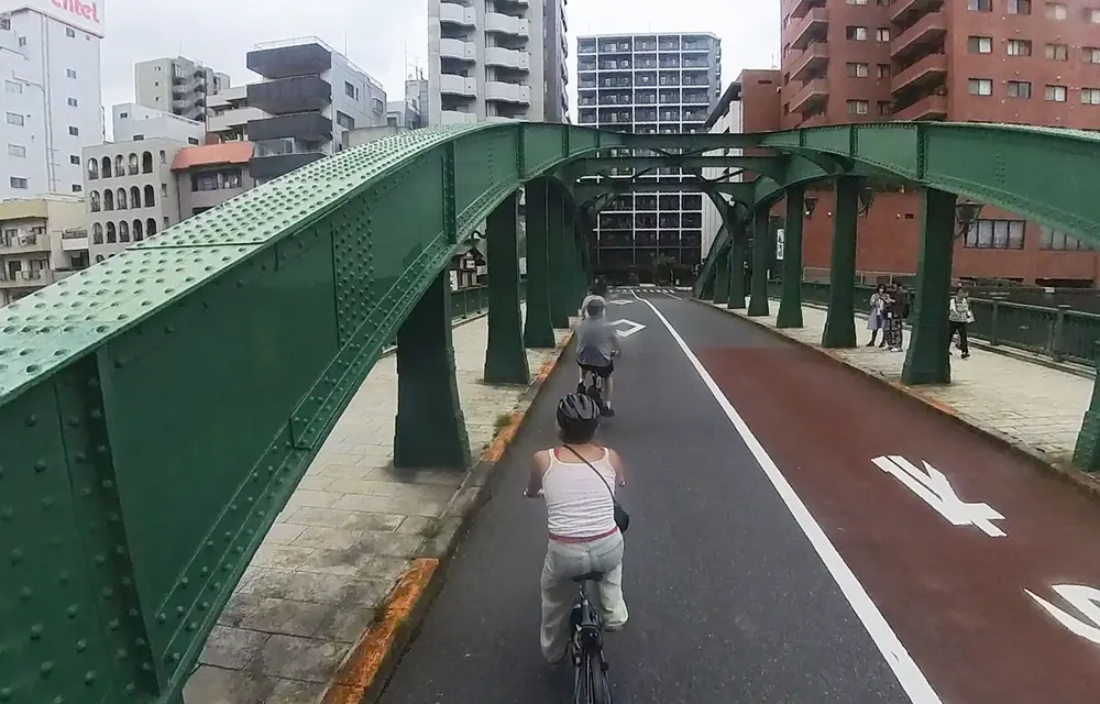Riding across a historic green iron bridge near Yanagibashi, Tokyo